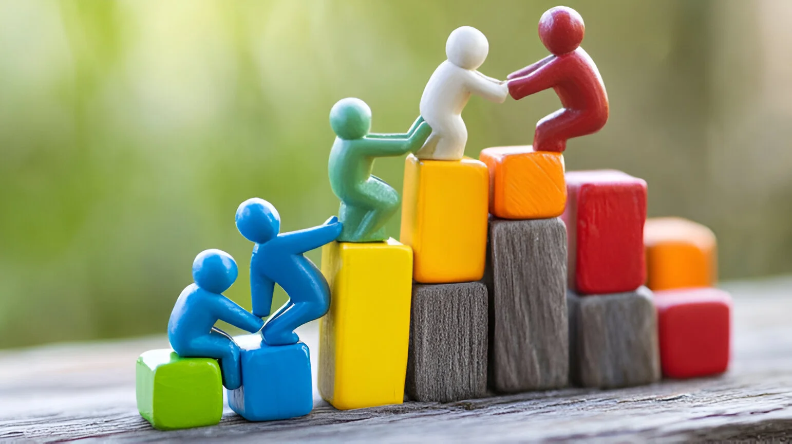 Team members helping each other climb steps, symbolizing leadership, teamwork, and organizational behaviour in change management.